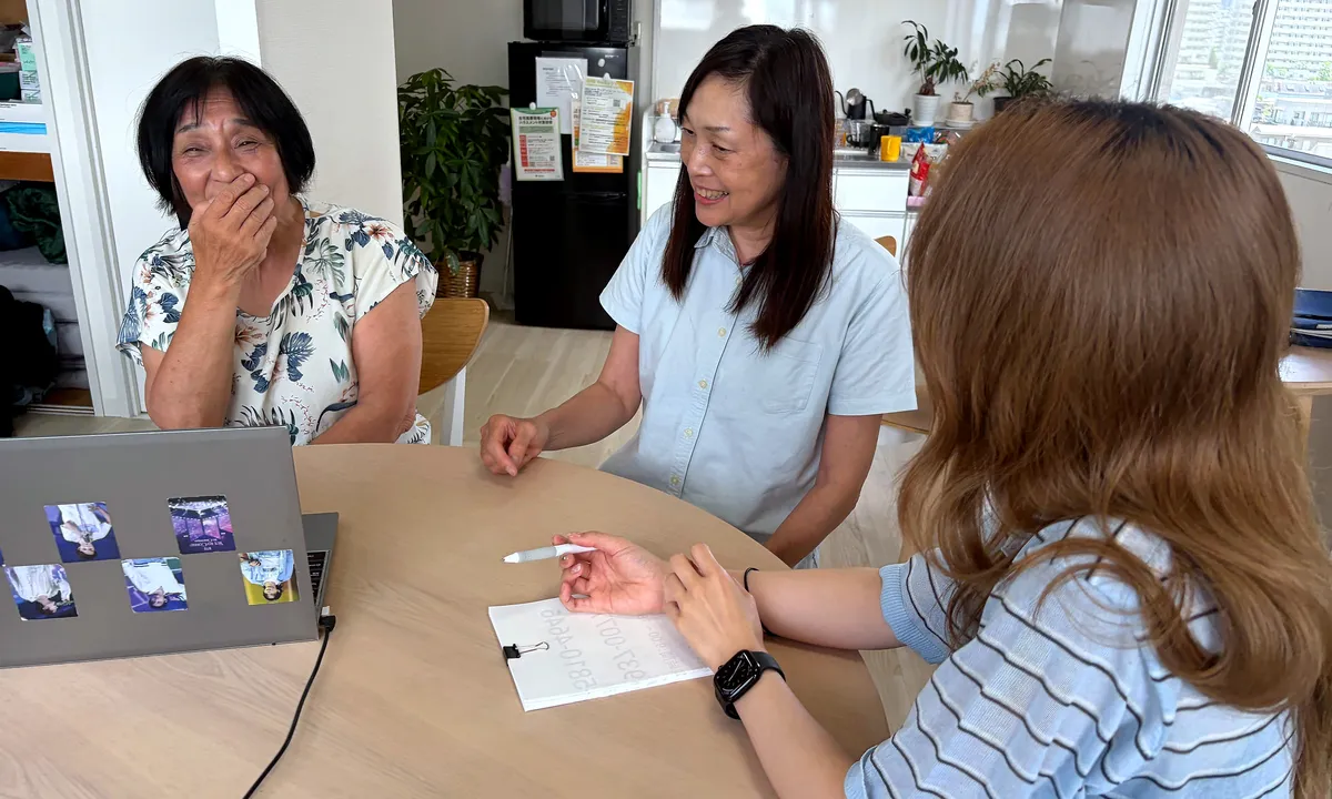 事務所の丸テーブルで笑いながら話しているケアマネジャーたち