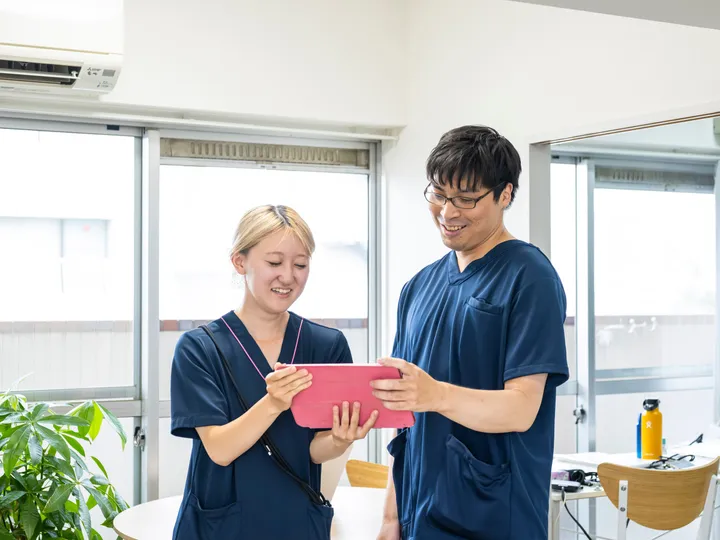 タブレットを一緒に見ながら業務内容を確認する2人の訪問看護スタッフ