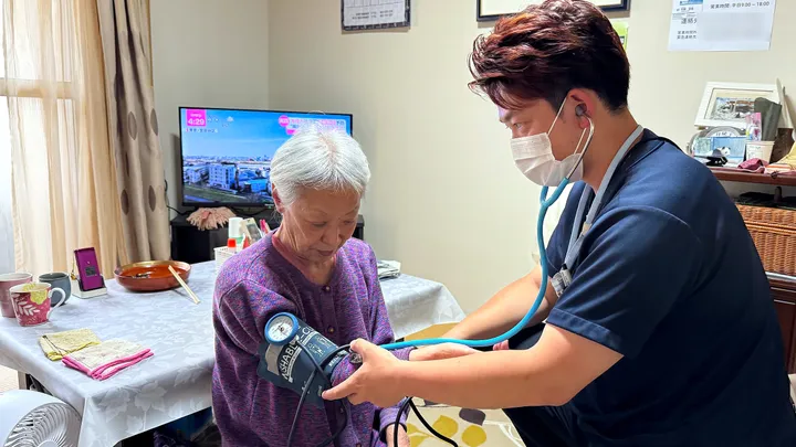 ご自宅で利用者さまの血圧を測る看護師